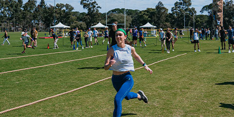 Female student wearing a green headband running on a track