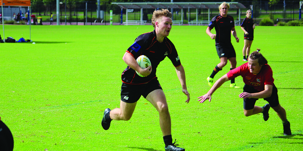 Athlete running while holding rugby ball on an oval