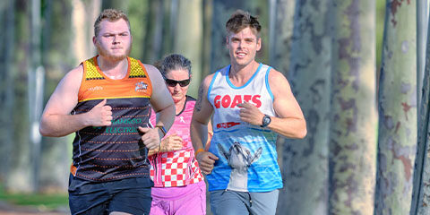 Student wearing a blue vest runs next to a student wearing an orange and black vest