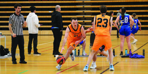 Student wearing orange shirt bounces a basketball in a stadium